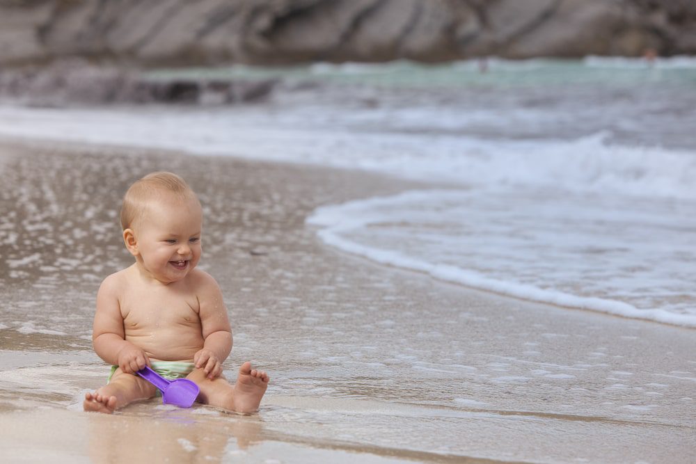 baby playing on the shore of the beach